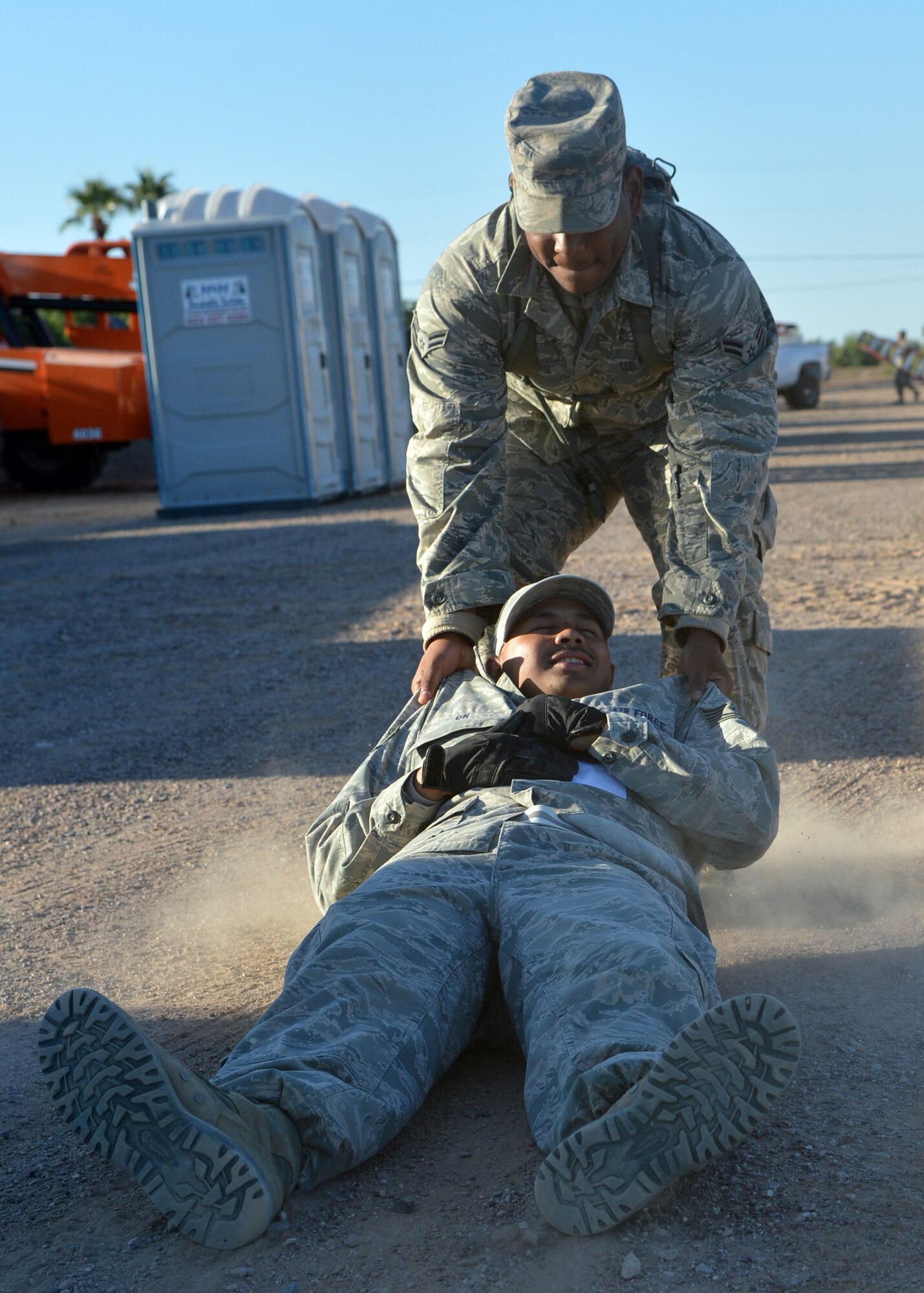 Airman 1st Class Carlton Mickles, 56th CES electrician, drags Tech. Sgt. Paul On, 56th CES energy programs specialist, to safety during a simulated ground attack at bivouac training in Gila Bend. Members of CES participated in a two-day mock deployment exercise focusing on force protection conditions and other essential learning tools. (U.S. Air Force photo/Airman 1st Class Devante Williams)