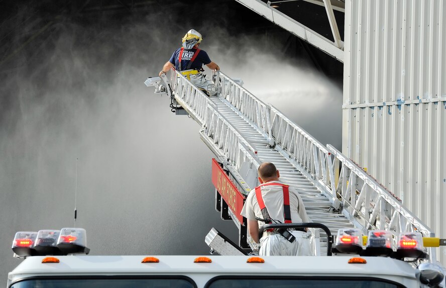 Mr. Barry Williams, a civilian fire fighter with the 436th Civil Engineer Squadron, Fire Department, works the nozzle of a ladder truck hose while perched on the elevated ladder on Sept. 16, 2013 at Dover Air Force Base, Del. Williams is spraying the foam to dissipate it so clean-up efforts can begin. (U.S. Air Force photo/Greg L. Davis)