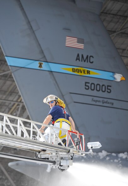 Mr. Barry Williams, a civilian fire fighter with the 436th Civil Engineer Squadron, Fire Department, works the nozzle of a ladder truck hose while perched on the elevated ladder on Sept. 16, 2013 at Dover Air Force Base, Del. Williams is spraying the foam to dissipate it so clean-up efforts can begin. (U.S. Air Force photo/Greg L. Davis)