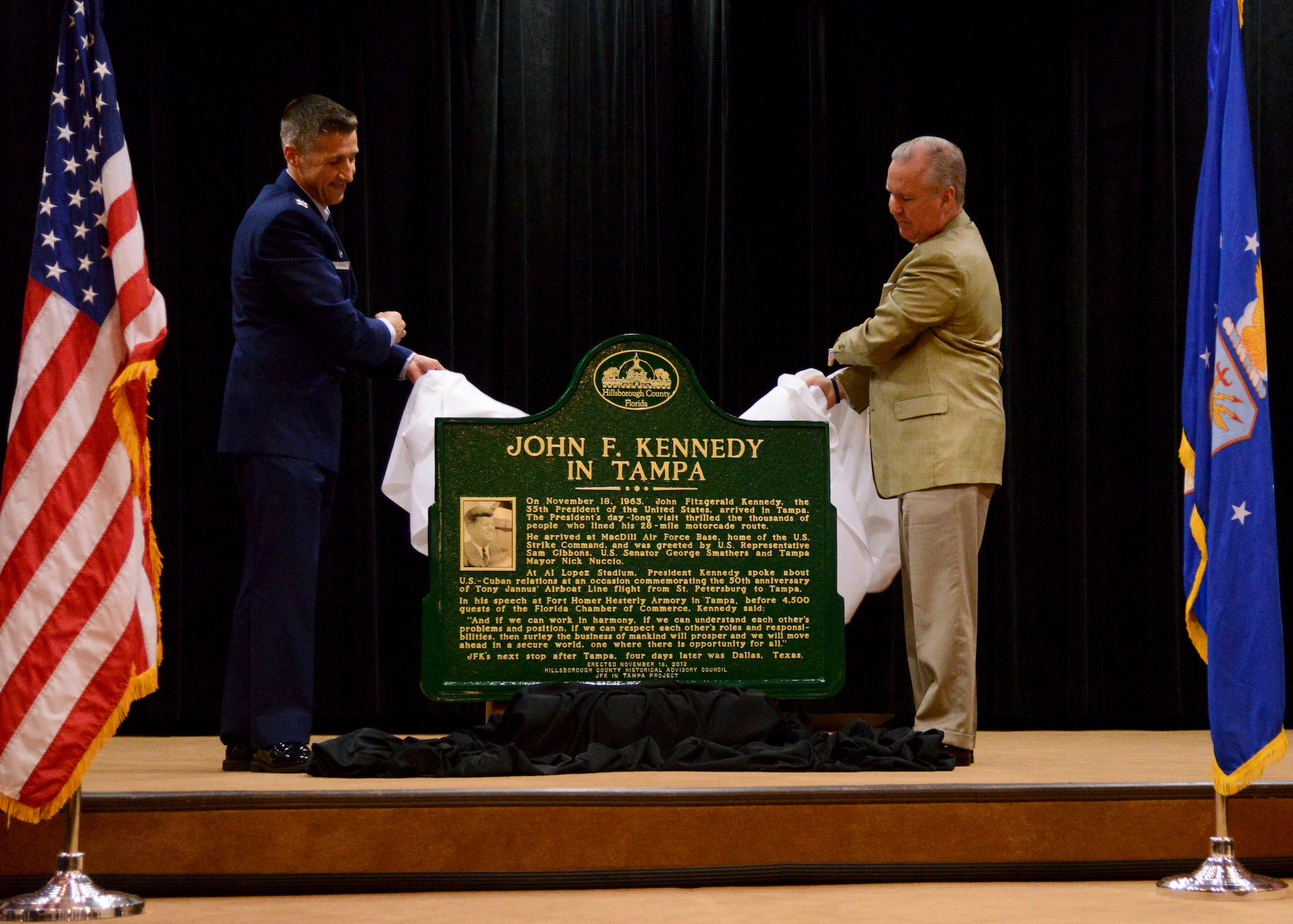 Col. Scott DeThomas, 6th Air Mobility Wing commander and Bob Buckhorn, mayor of Tampa, unveil a plaque in honor of John F. Kennedy during a commemorative ceremony Nov. 18, 2013 at MacDill Air Force Base, Fla. MacDill and the city of Tampa was the last place President Kennedy visited before his untimely death in 1963.(U.S. Air Force photo by Senior Airman Jenay Randolph/Released)