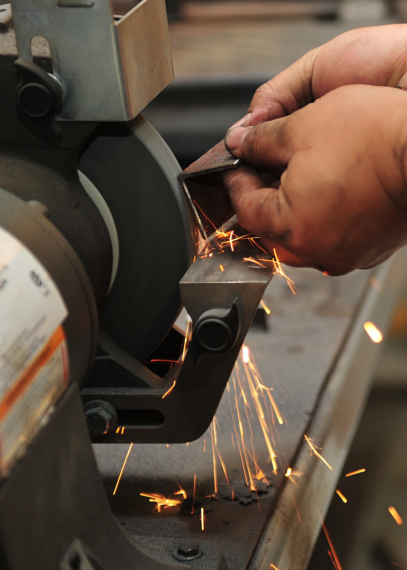 U.S. Air Force Senior Airman Hyung Kil, 380th Expeditionary Logistics Readiness Squadron vehicle maintenance technician, grinds the edges of a metal bracket in the vehicle maintenance facility at an undisclosed location in Southwest Asia, Nov. 21, 2013. Vehicle technicians are also required to know welding, grinding, hydraulics, electrical systems, diagnostics and emissions. Kil is deployed from Mountain Home Air Force Base, Idaho. (U.S. Air Force photo by Staff Sgt. Michael Means/Released)