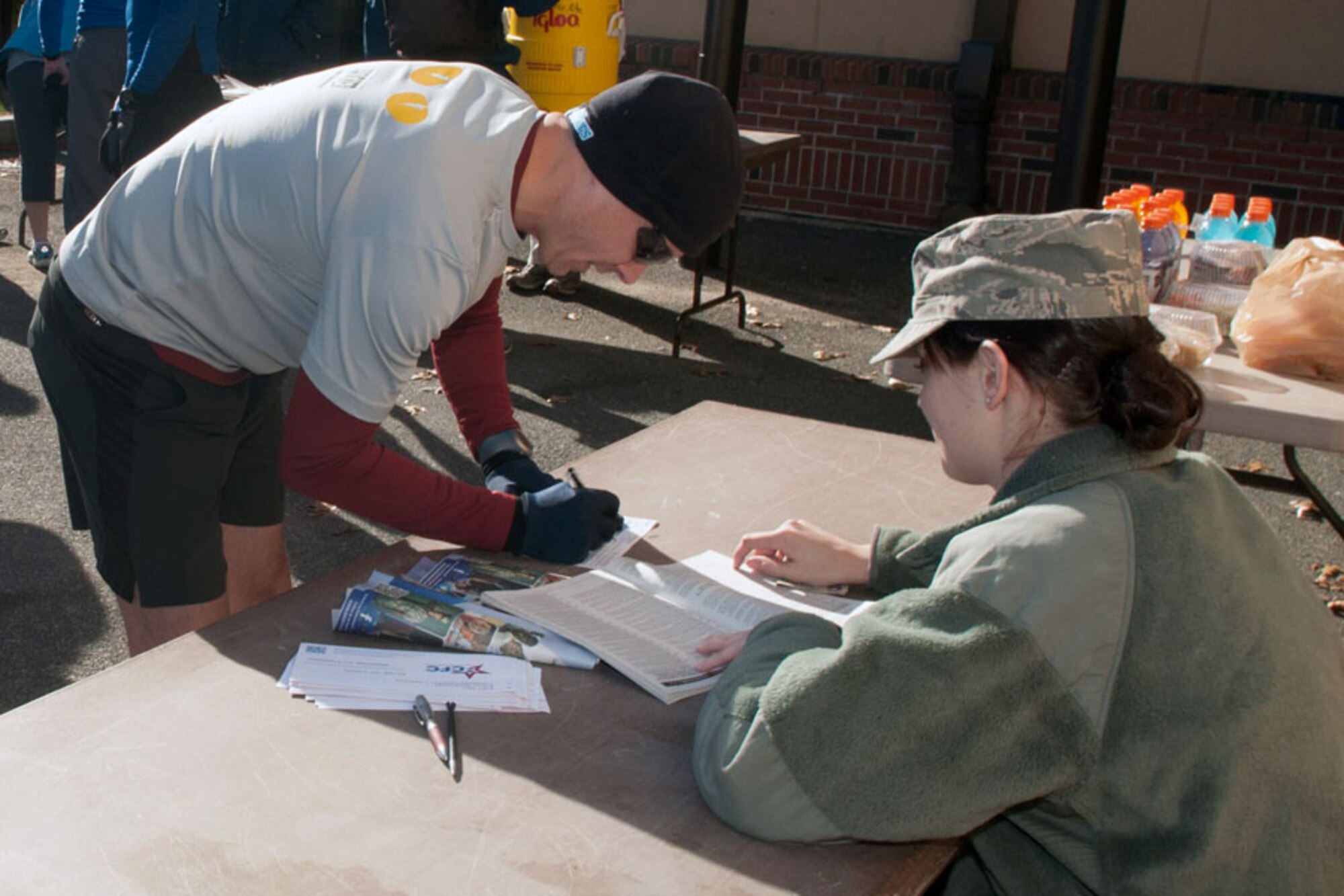 HANSCOM AIR FORCE BASE, Mass. – Philip Harting, Battle Management Mission Planning Program Office program manager, signs a Combined Federal Campaign pledge form at the Turkey Trot 5K Fun Run at the Fitness and Sports Center Nov. 20 as 2nd Lt. Claire Davis, Hanscom’s CFC manager, looks on. The Fitness Center and CFC organizers teamed up during the monthly event to raise more than $1,000 towards the CFC goal. The campaign continues through Dec. 13. (U.S. Air Force photo by Rick Berry)