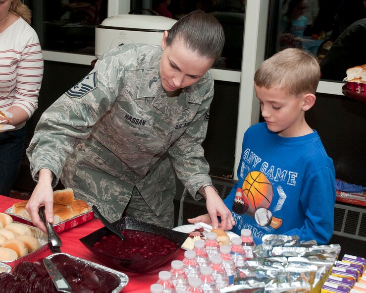 HANSCOM AIR FORCE BASE, Mass. – Master Sgt. Pattie Hassan, Air Force Life Cycle Management Center, Detachment 7 first sergeant, assists Brady Watkins with his dinner at a Thanksgiving themed Hearts Apart event at the Minuteman Commons, Nov. 14. The Integrated Delivery System team co-sponsored this month’s event for deployed and extended travel family members with the Airman and Family Readiness Center.  (Courtesy photo)