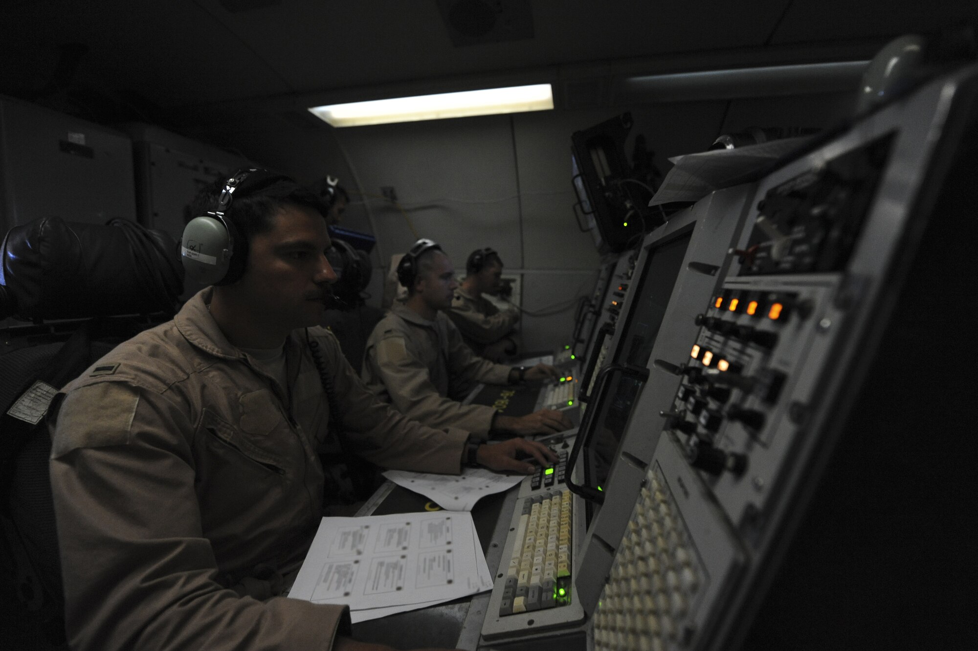 Three air weapons officers from the 968th Expeditionary Airborne Air Control Squadron sit infront of their consoles, or scopes, where they are monitoring aircraft movement while in flight on an E-3 Sentry at an undisclosed location in Southwest Asia Nov. 16, 2013. While in flight, the AWOs are responsible for controlling friendly aircraft providing them a full battlespace picture. (U.S. Air Force photo by Staff Sgt. Jacob Morgan)