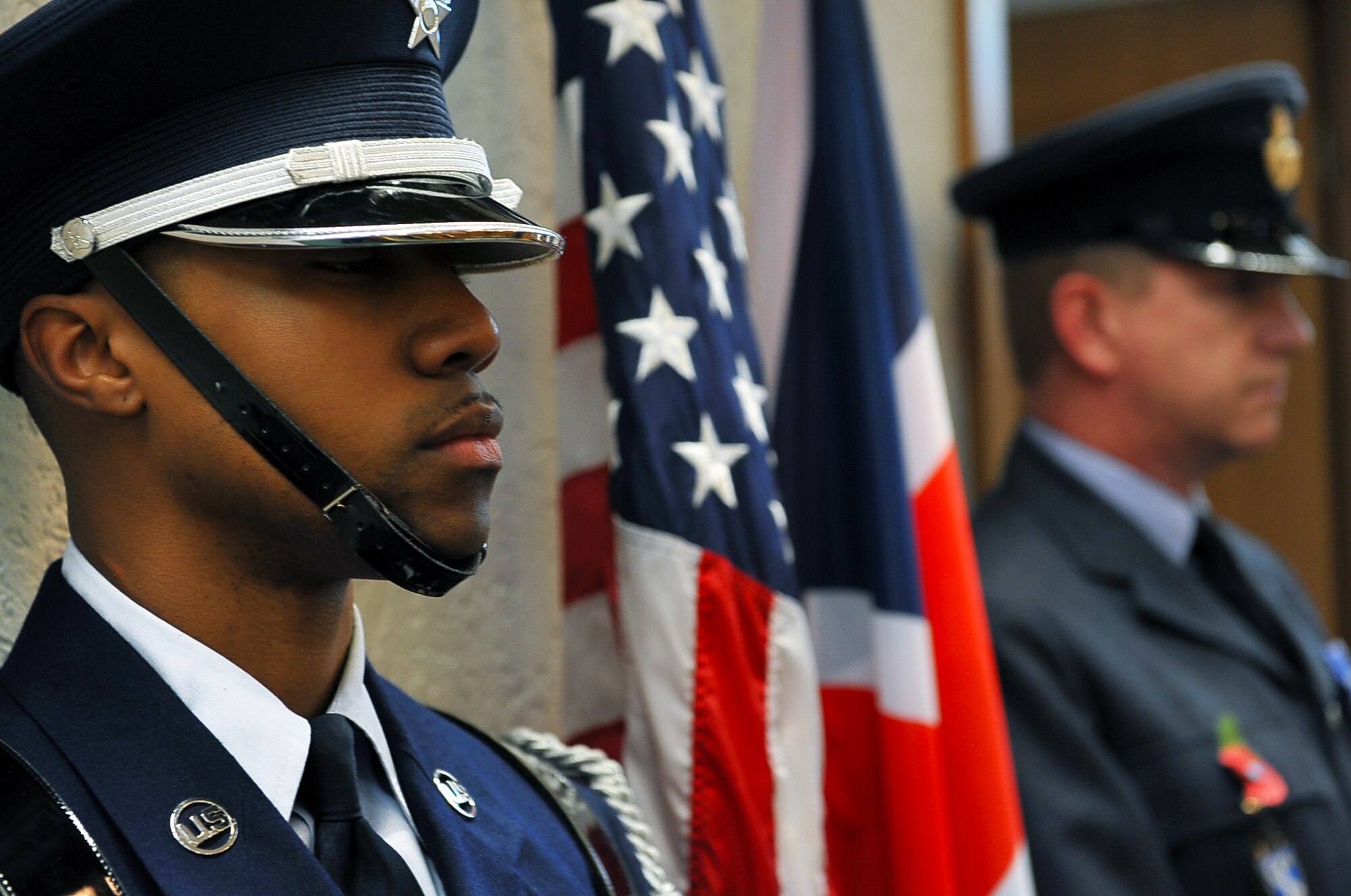 Senior Airman Quinten Brewer, 786th Force Support Squadron honor guardsman, and a Kellick Michael, German guardsman, waits for his cue to begin the colors ceremony, Nov. 17, 2013, Ramstein Air Base, Germany. The base honor guard trains constantly to perfect and hone their skills so they maintain readiness for ceremonies they conduct. (U.S. Air Force photo/Airman Dymekre Allen)