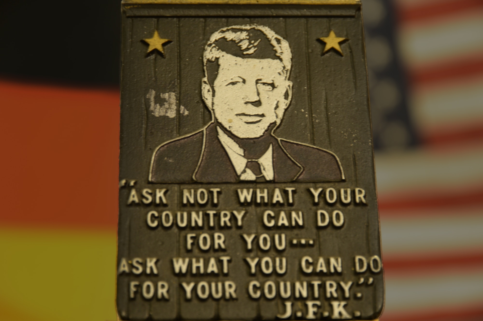 SPANGDAHLEM AIR BASE GERMANY--- A memorial plaque featuring U.S. President John F. Kennedy and a quote from his 1961 inaugural address is displayed in front of the German and American flags Nov. 21, 2013.  Kennedy was assassinated during a presidential motorcade in Dallas, Texas, Nov. 22, 1963. (U.S. Air Force photo illustration by Staff Sgt. Joe W. McFadden / Released)