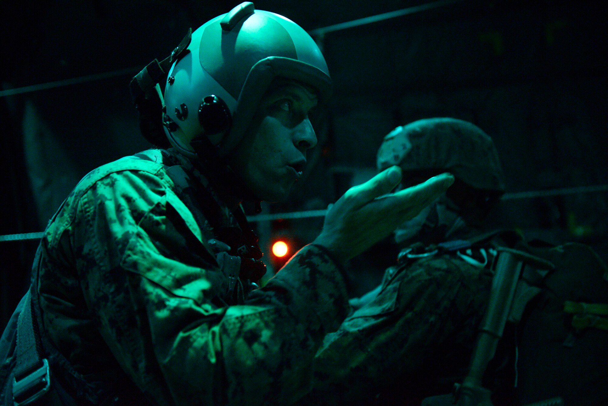 A Marine uses hand signals to communicate with other Marine jumpers in a C-130 Hercules over Yokota Air Base, Japan, Nov. 21, 2013. The Marines were conducting a night jump as part of their yearly jump currency. (U.S. Air Force by Senior Airman Cody H. Ramirez)