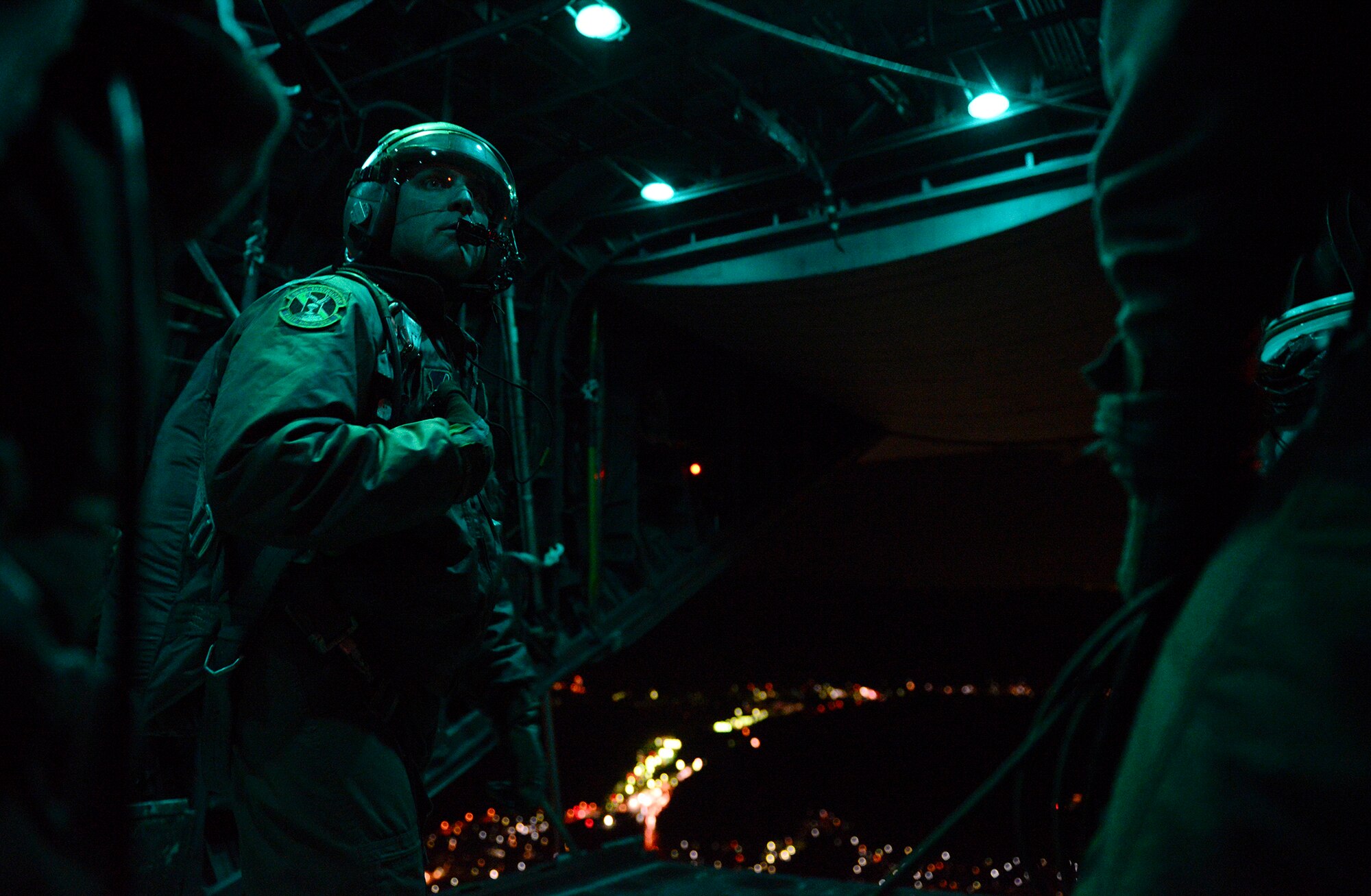 A loadmaster with the 36th Airlift Squadron communicates drop times with C-130 Hercules pilots during a night jump at Yokota Air Base, Japan, Nov. 21, 2013. The jumpers were Marines with the 3rd Reconnaissance Battalion, 3rd Marine Division, 3rd Marine Expeditionary Force. (U.S. Air Force photo by Senior Airman Cody H. Ramirez)