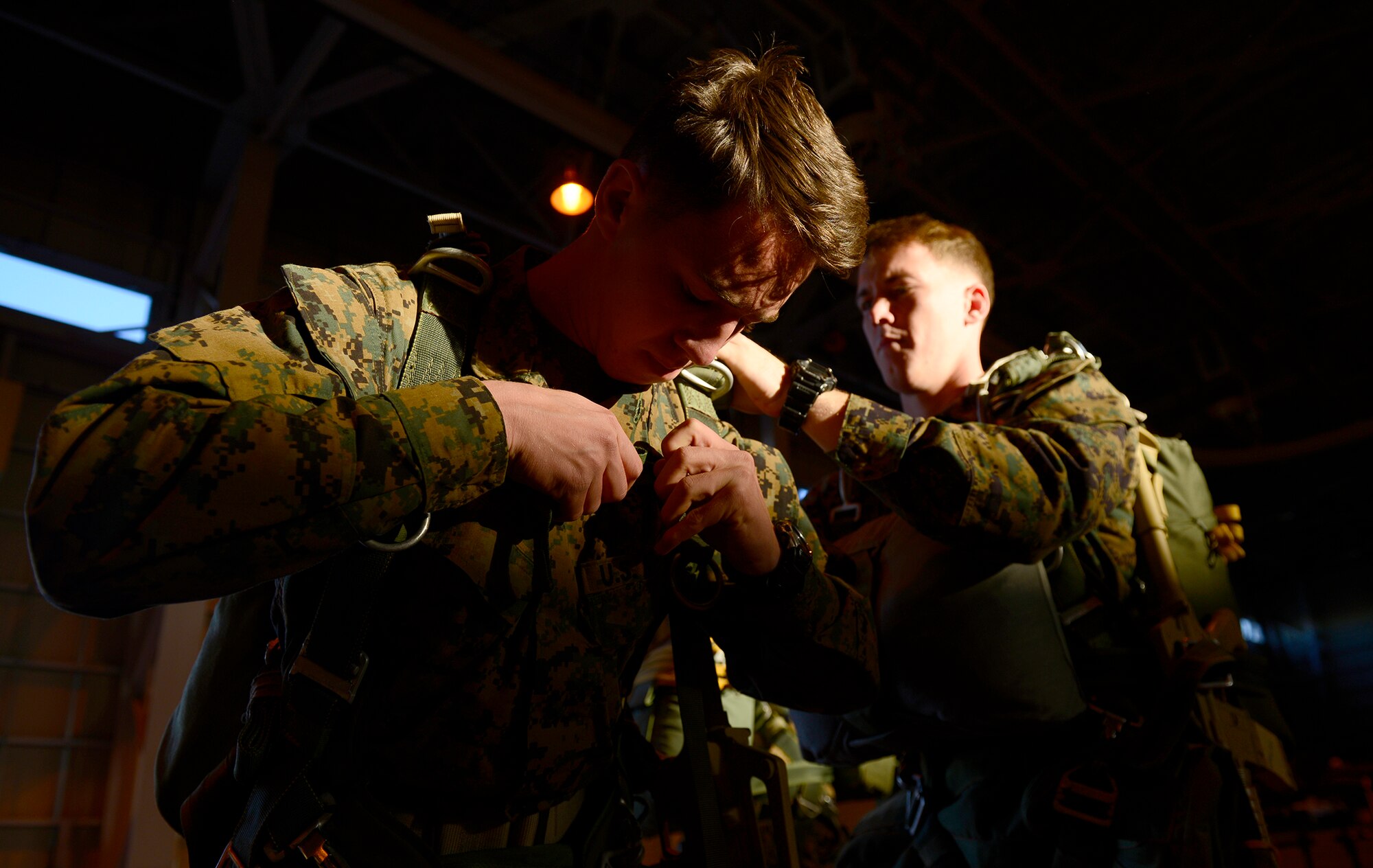 Marines hit with the last remaining beams of light check each other’s gear before a night jump at Yokota Air Base, Japan, Nov. 21, 2013. The Marines, with the 3rd Reconnaissance Battalion, 3rd Marine Division, 3rd Marine Expeditionary Force, were at Yokota to maintain jump currency. (U.S. Air Force photo by Senior Airman Cody H. Ramirez)