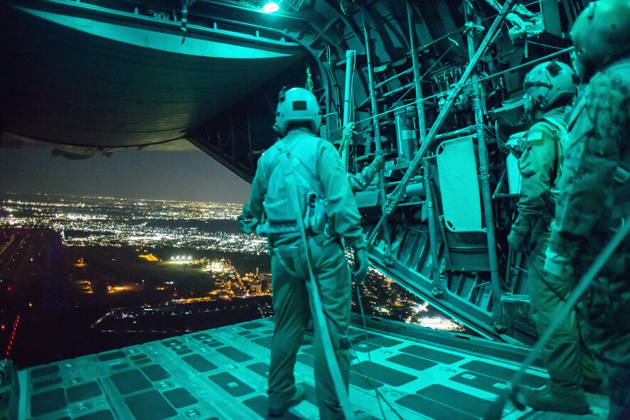 Marines with the 3rd Reconnaissance Battalion, 3rd Marine Division, III Marine Expeditionary Force and an Airman from the 36th Airlift Squadron, observe Marine paratroopers after jumping from a C-130 Hercules over Yokota Air Base, Japan, Nov. 21, 2013. The training not only allowed the marines to practice jumping, but it also allowed the Yokota aircrews to practice flight tactics and timed-package drops. (U.S. Air Force photo by Osakabe Yasuo/Released)