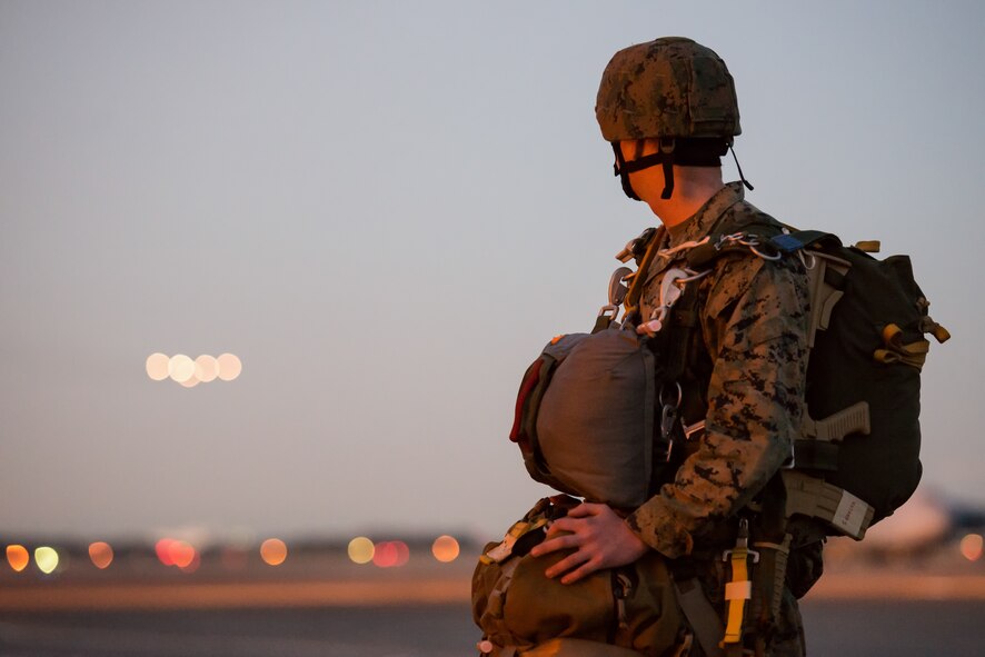 A Marine with the 3rd Reconnaissance Battalion, 3rd Marine Division, III Marine Expeditionary Force watches a C-130 Hercules at Yokota Air Base, Japan, Nov. 21, 2013. The training not only allowed the marines to practice jumping, but it also allowed the Yokota aircrews to practice flight tactics and timed-package drops. (U.S. Air Force photo by Osakabe Yasuo/Released)