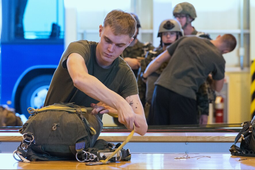 Marines with the 3rd Reconnaissance Battalion, 3rd Marine Division, III Marine Expeditionary Force, inspect a parachute at Yokota Air Base, Japan, Nov. 21, 2013. The training not only allowed the marines to practice jumping, but it also allowed the Yokota aircrews to practice flight tactics and timed-package drops. (U.S. Air Force photo by Osakabe Yasuo/Released)