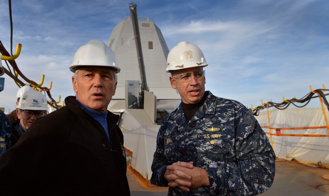 Defense Secretary Chuck Hagel, left, talks with Navy Capt. James A. Kirk, commander of the USS Zumwalt, as he tours the ship's forward deck at Bath Iron Works in Bath, Maine, Nov. 21, 2013.