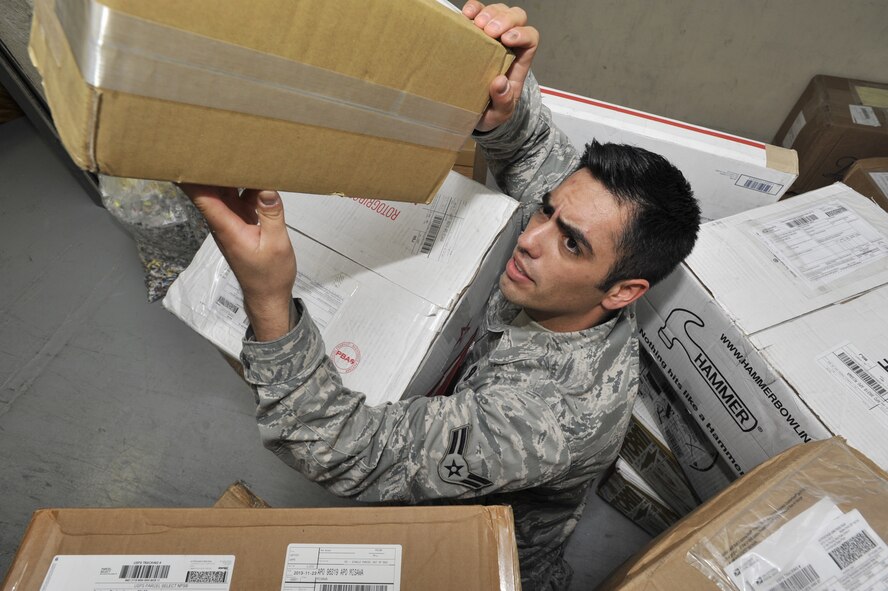 MISAWA AIR BASE, Japan -- Airman 1st Class Julian Bran, 35th Communication Squadron postal clerk, stacks packages to make room for more incoming mail. From mid-November to mid-January the post office receives and delivers more than 640,000 pounds of mail, more than four times their normal capacity. With the holiday mailing season under full swing, the Post Office has extended its hours of operation to allow customers more time to send or pick up packages. (U.S. Air Force Photo Illustration by Staff Sgt. Tong Duong/ Released) 