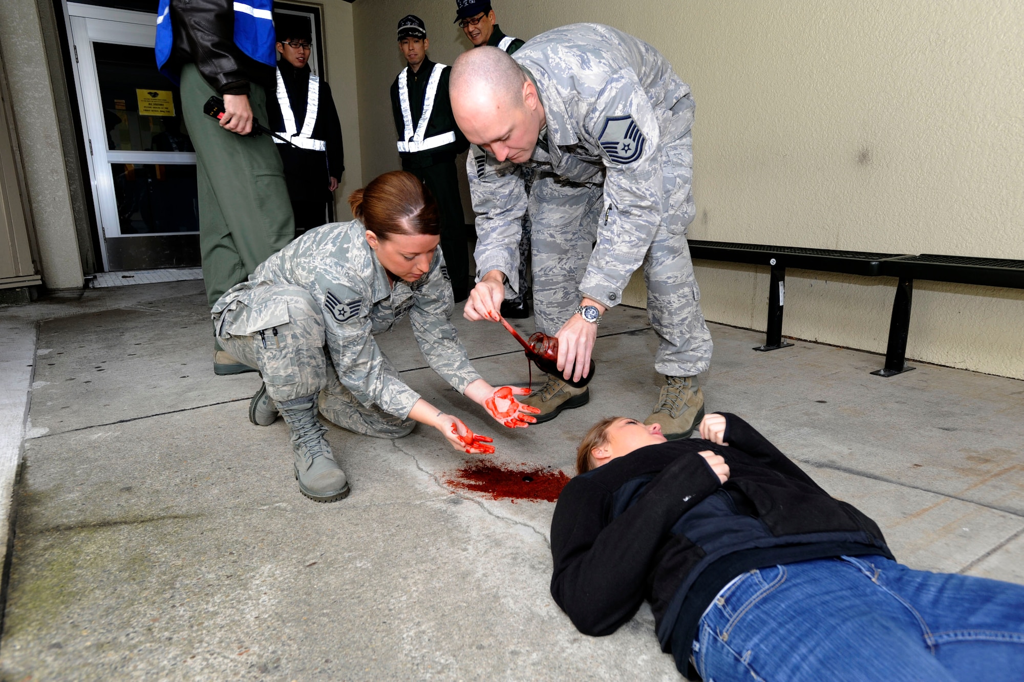 MISAWA AIR BASE, Japan -- Master Sgt. Bradley Reeves, 35th Medical Group and Staff Sgt. Jennifer Dye, 35th Dental Squadron, moulage artists apply fake blood to a simulated victim during an Active Shooter Emergency Management Exercise, at Edgren High School, Nov. 20, 2013. Creating a realistic scene gives exercise participants a visualization of a real world incident, adding an additional level of stress to their training. (U.S. Air Force photo by Staff Sgt. Tong Duong/ Released)