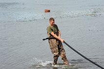 Marine Lance Cpl. Richard Frederick from the 9th Engineer Support Battalion moves a raw water purification pump hose to allow for easier flow of water to the purifier. Marines have purified more than 100,000 gallons of water for use by Typhoon Haiyan victims.