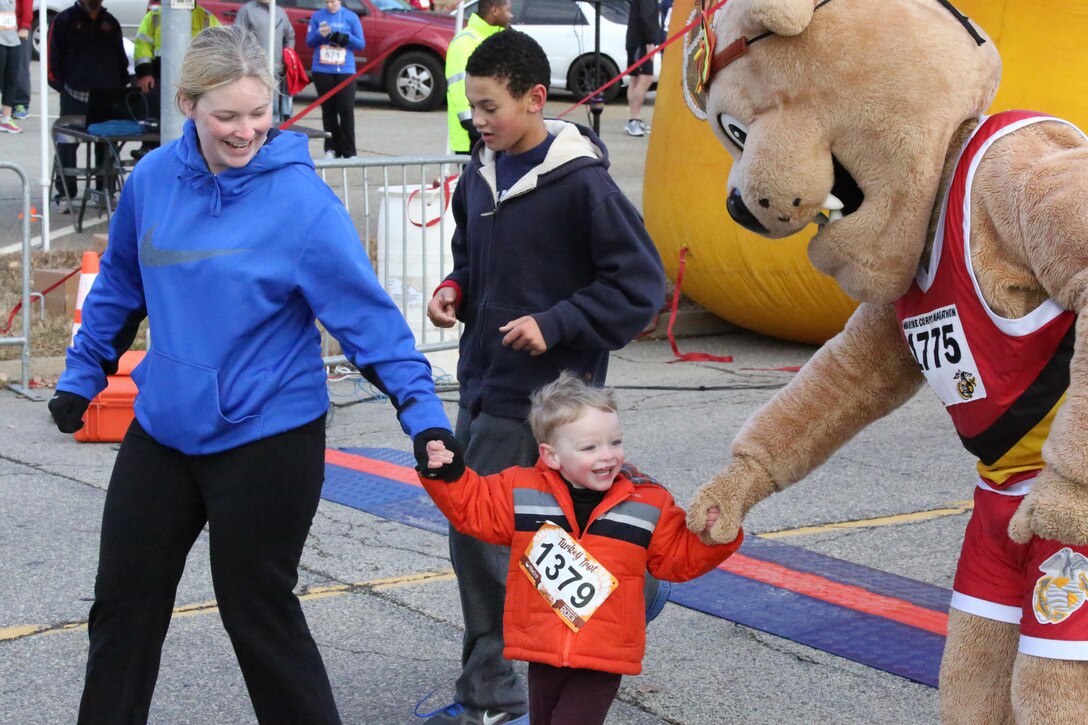 Miles, the Marine Corps Marathon mascot, motivates a runner during the Turkey Trot Mile aboard Marine Corps Base Quantico on Nov. 23, 2013. Over 1,000 people participated in the event. 