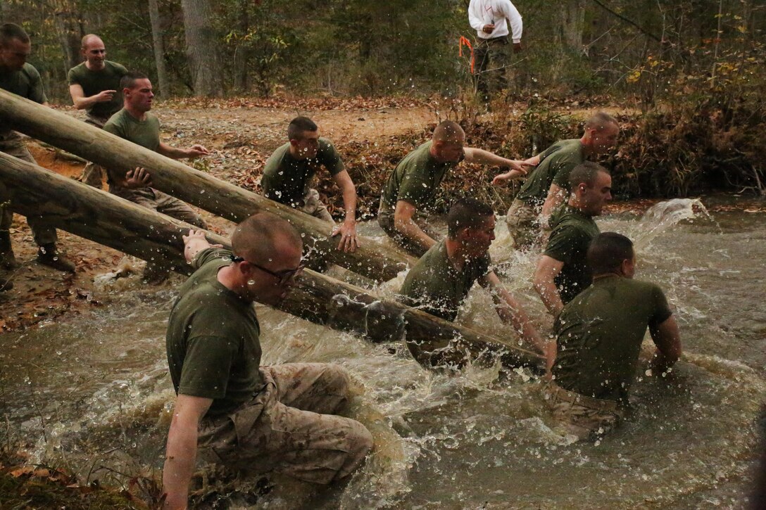 Marine candidates jump into water while transporting logs during a field meet at Officer Candidates School on Nov. 21, 2013. The field meet is one of the final events candidates participate in before graduation.