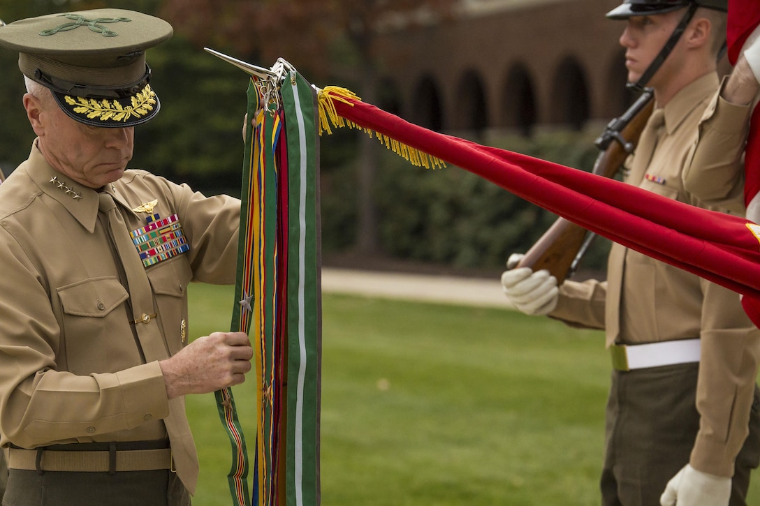Gen. James F. Amos, commandant of the Marine Corps, left, attaches a Navy Meritorious Unit Commendation streamer to Marine Barracks Washington, D.C. battle colors during an unit award presentation at the Barracks Nov. 22. The Barracks earned the award for its performance in support of multiple major events around the national capital region. 