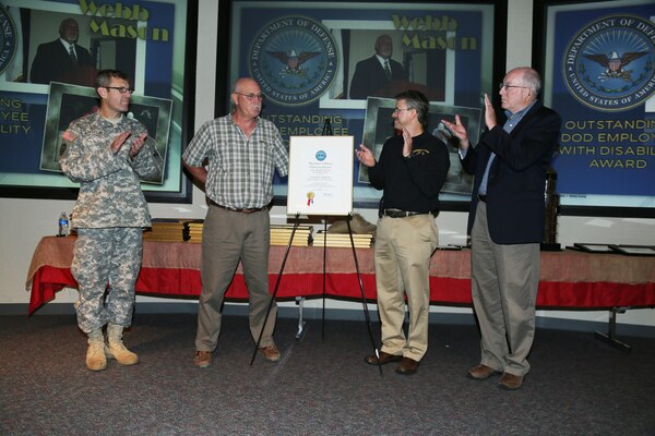 From left, ERDC Commander COL Jeffrey Eckstein, Webb Mason, Geotechnical and Structures Laboratory Director Dr. David Pittman and ERDC Director Dr. Jeff Holland react to the unveiling of Mason's 2013 Outstanding Department of Defense Employee with a Disability Award. 