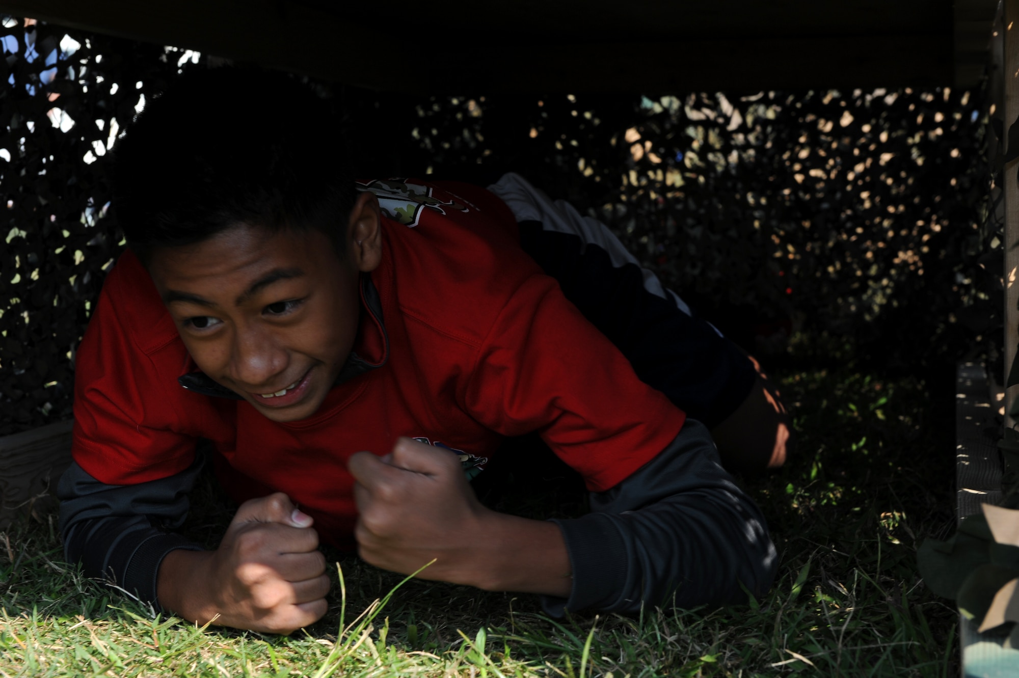 A Skoshi Warrior participant crawls through a tunnel in an obstacle course during the event on Kadena Air Base, Japan, Nov. 23, 2013. More than 200 children participated in Skoshi Warrior, an annual event hosted by the 18th Force Support Squadron to provide a realistic, yet fun, depiction of the deployment process. During the event, participants walk through processing lines, learn facing movements and how to properly wear chemical protective equipment. (U.S. Air Force photo by Airman 1st Class Hailey R. Davis)