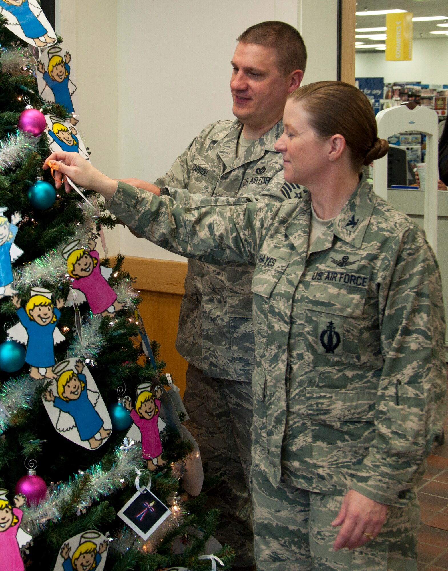 Col. Tracey Hayes, 90th Missile Wing commander and Chief Master Sgt. Michael Garrou, 90th MW Command Chief, select an “angel ornament” from the Angel Tree during the Angel Tree Program kick-off ceremony in the F.E. Warren Base Exchange Nov. 25, 2013. Warren’s First Sergeant’s Council sponsors the program which provides assistance to local families in need during the holidays. The Angel Tree, located in the Exchange, contains the wishes of 112 children, 30 of them from deployed families. On each “angel ornament,” an information card contains a child’s age, gender, clothing sizes and special gift requests. Donating individuals may choose one or more angels and purchase unwrapped gifts with the angel attached to them. The gifts are then left in the box next to the Angel Tree and will be delivered to the identified families at the end of the campaign, Dec. 9, 2013. (U.S. Air Force photo by Tech. Sgt. Stacy Foster)