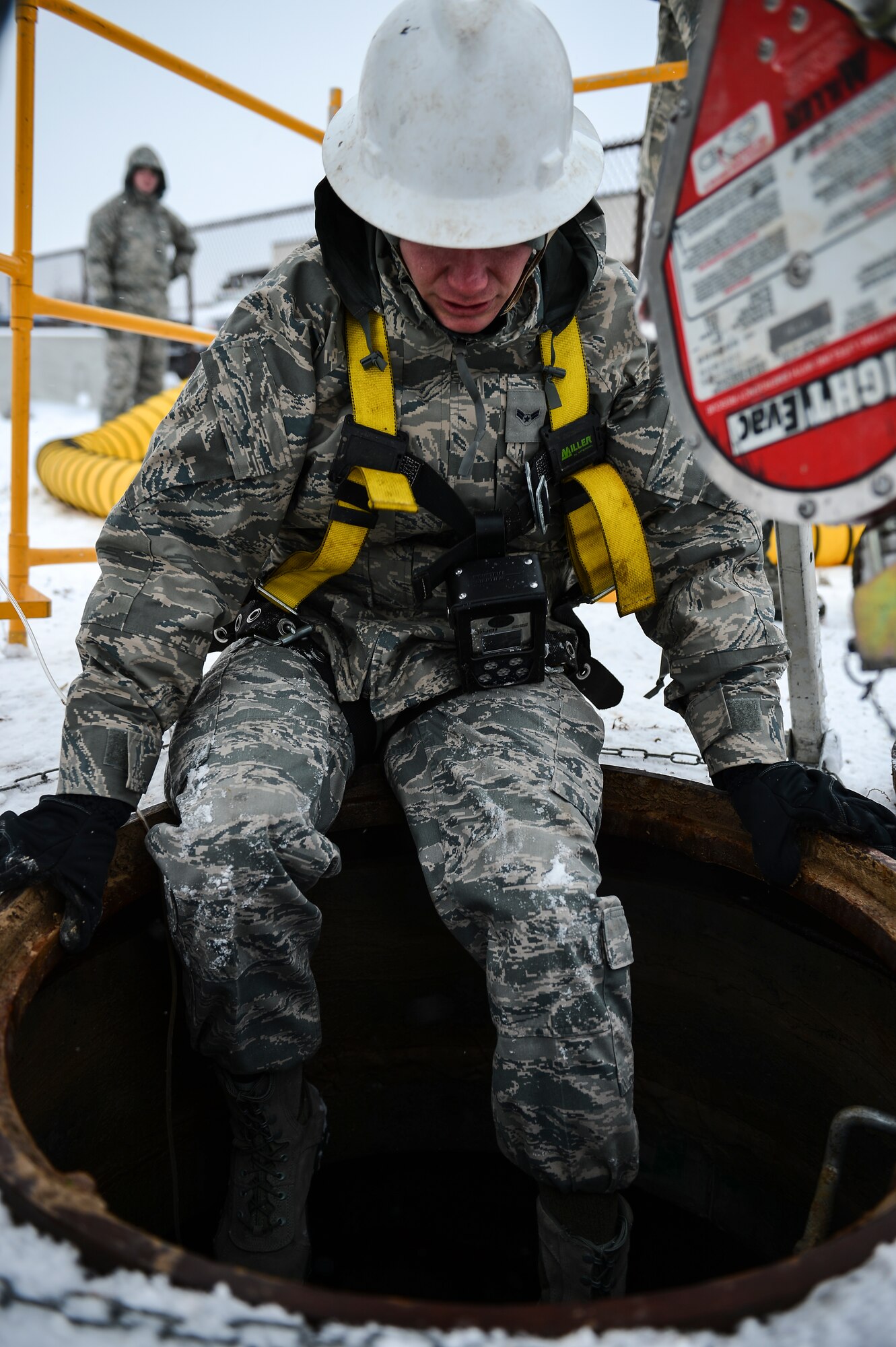 Airman 1st Class Aaron Thompson, 460th Space Communications Squadron cable antenna systems technician, climbs into a manhole for confined-spaces training Nov. 21, 2013, near the 460th SCS building on Buckley Air Force Base, Colo. Regardless of the weather, cable antenna systems technicians are required to complete confined-spaces training as part of on-the-job training. (U.S. Air Force photo by Senior Airman Riley Johnson/Released)