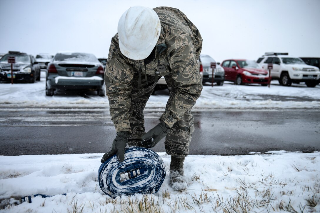 Senior Airman Lucas Maddox, 460th Space Communications Squadron cable antenna systems technician, rolls up a hose during confined-spaces training Nov. 21, 2013, near the 460th SCS building on Buckley Air Force Base, Colo. Regardless of the weather, cable antenna systems technicians are required to complete confined-spaces training as part of on-the-job training. (U.S. Air Force photo by Senior Airman Riley Johnson/Released)