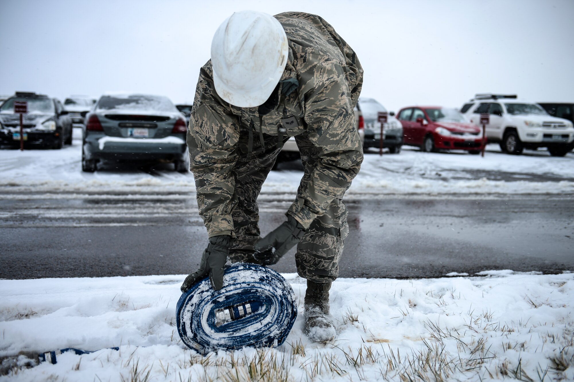 Senior Airman Lucas Maddox, 460th Space Communications Squadron cable antenna systems technician, rolls up a hose during confined-spaces training Nov. 21, 2013, near the 460th SCS building on Buckley Air Force Base, Colo. Regardless of the weather, cable antenna systems technicians are required to complete confined-spaces training as part of on-the-job training. (U.S. Air Force photo by Senior Airman Riley Johnson/Released)