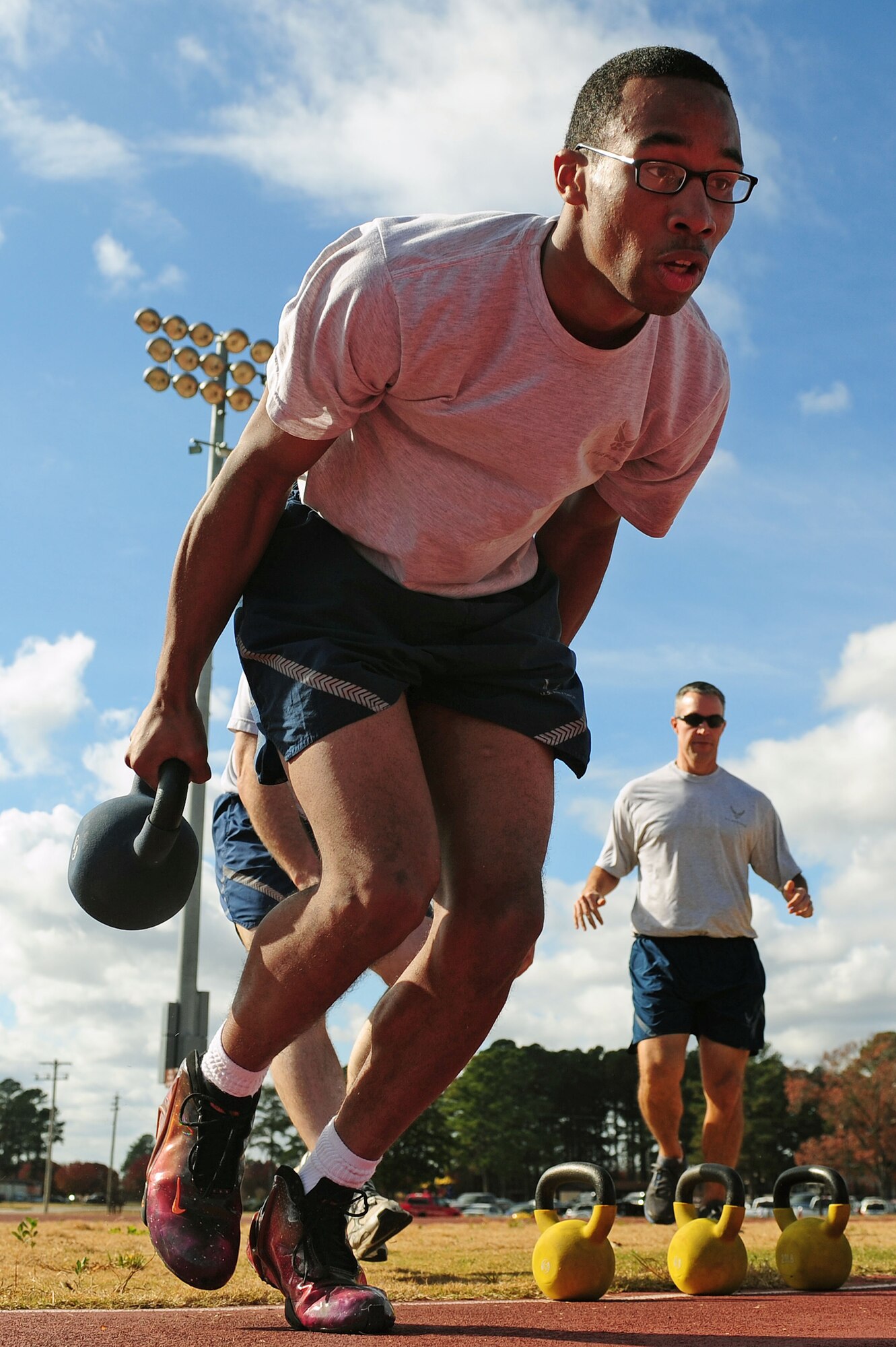 A U.S. Air Force Airman assigned to the 4th Fighter wing carries two 40-pound kettle bells while competing a commander’s challenge event during a Comprehensive Airmen Fitness (CAF) Day event at Seymour Johnson Air Force Base, N.C., Nov. 22, 2013. The CAF program was designed to improve well-being and enhance life balance for the military community. (U.S. Air Force photo by Airman 1st Class John Nieves Camacho/Not Released)