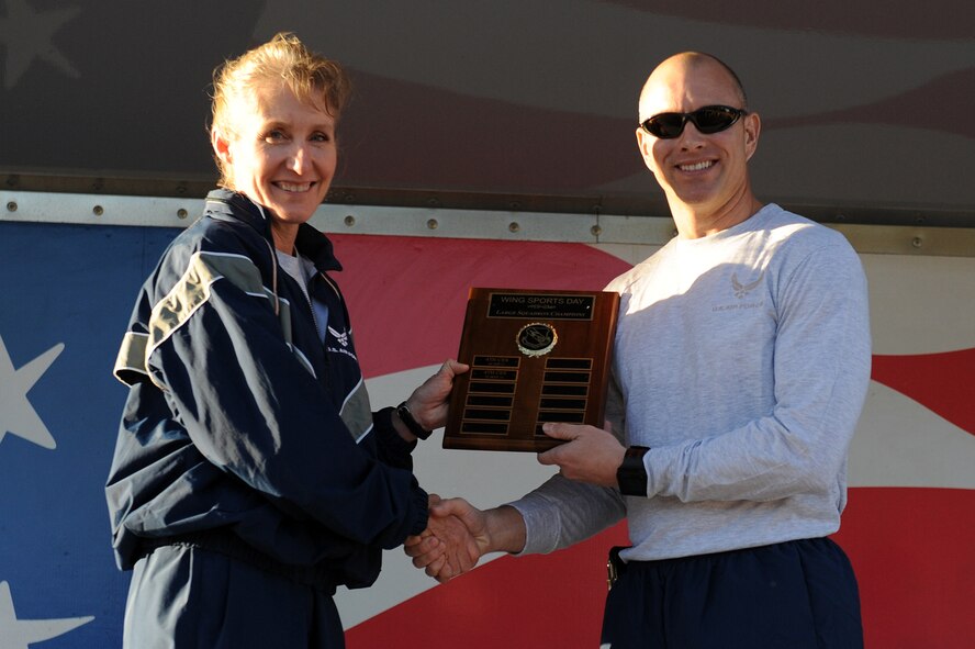 U.S. Air Force Lt. Col. Dave Pike, 911th Air Refueling Squadron commander, receives the large-squadron championship award from Col. Jeannie Leavitt, 4th Fighter Wing commander, for the squadron’s overall success in the wing’s Comprehensive Airman Fitness (CAF) D ay at Seymour Johnson Air Force Base, N.C., Nov. 22, 2013. Once a quarter, the 4th FW holds a CAF day to focus on building physical, mental, social and spiritual strengths to improve resiliency. (U.S. Air Force photo by Airman 1st Class Aaron J. Jenne)