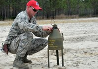 Tech. Sgt. Joseph Dwan, 823rd RED HORSE Squadron heavy equipment and construction supervisor, tapes detonating cord to the top of a shape charge at the explosive ordnance disposal range on Hurlburt Field, Fla., Nov. 21, 2013. The shaped charges made initial holes in the ground by directing the force of the explosion downward. (U.S. Air Force photo/Senior Airman Kentavist P. Brackin)