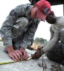 Staff Sgt. Michael Miller and Senior Airman Antoine Davis, 823rd RED HORSE Squadron pavement and construction equipment operators, measure a piece of detonating cord at the explosive ordnance disposal range on Hurlburt Field, Fla., Nov. 21, 2013. The cords required precise measurements to ensure the demolition team had adequate time to evacuate during timed detonations. (U.S. Air Force photo/Senior Airman Kentavist P. Brackin)