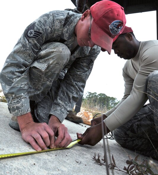Staff Sgt. Michael Miller and Senior Airman Antoine Davis, 823rd RED HORSE Squadron pavement and construction equipment operators, measure a piece of detonating cord at the explosive ordnance disposal range on Hurlburt Field, Fla., Nov. 21, 2013. The cords required precise measurements to ensure the demolition team had adequate time to evacuate during timed detonations. (U.S. Air Force photo/Senior Airman Kentavist P. Brackin)