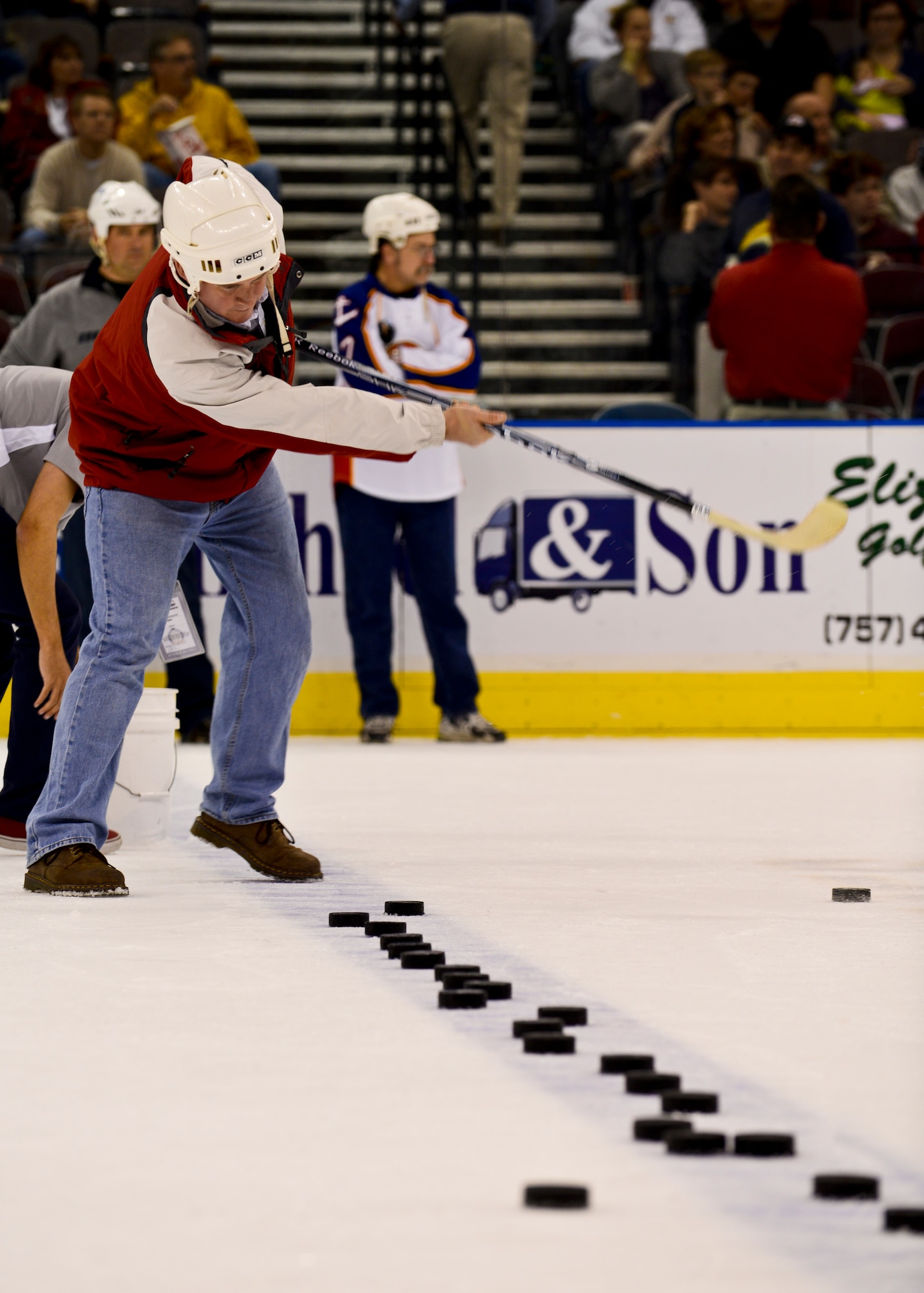 An event attendee shoots pucks toward the goal to win a prize the Norfolk Admirals Military Appreciation Night hockey game in Norfolk, Va., Nov. 22, 2013.  In honor of Military Appreciation Night, the Norfolk Scope ice arena partnered with USAA and offered discounted tickets to Service members. (U.S. Air Force photo by Airman 1st Class Victoria H. Taylor/Released)