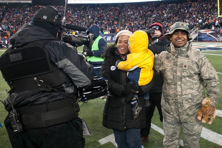 FOXBOROUGH, Mass. -- Maj. Wellington Phillips II and his wife Dahlia and 19 month old son Wellington are all smiles as they walk off the field at Gillette Stadium here after a surprise reunion during the New England Patriots and Denver Broncos Sunday Night Football game Nov. 24. Phillips, who is returning from a six month deployment, surprised his family during a halftime ceremony. Phillips is assigned to the Air Force Life Cycle Management Center-Hanscom. (U.S. Air Force photo by Rick Berry)
