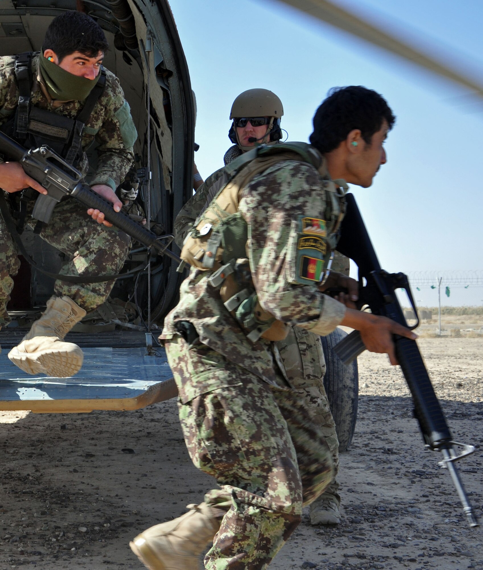 U.S. Air Force Staff Sgt. Mark Cornett, 441st Air Expeditionary Advisory Squadron special mission aviator, guides Afghan Air Force security forces members off a Mi-17 helicopter Nov. 10, 2013 near Kandahar Airfield, Afghanistan. The security forces members conducted fly away security training, including infiltration and exfiltration, cold load training, where the Airmen practice loading and unloading without helicopter blades running, and hot load training, where the blades are running. The class was led by Master Sgts. Patrick Flores and Olivia McMahon, 443rd Air Expeditionary Advisory Squadron security forces. (U.S. Air Force photo/Capt. Anastasia Wasem)