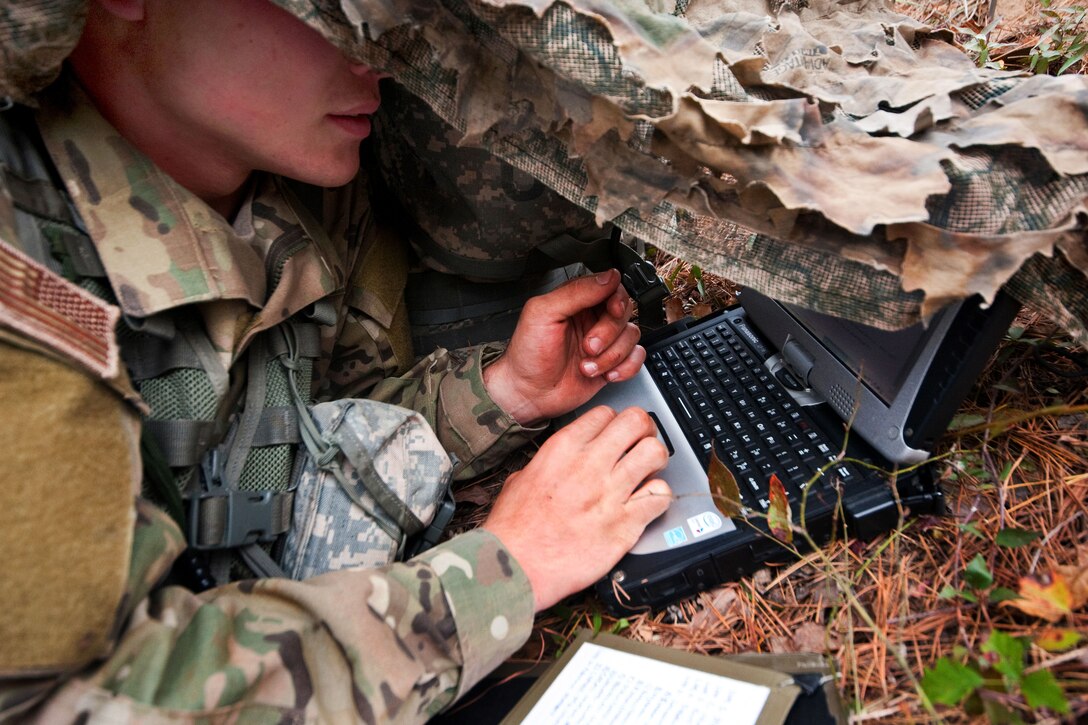 Under concealment, a soldier uses a laptop for communication and surveillance during phase two of the Reconnaissance Surveillance Leaders Course on Fort Benning, Ga., Nov. 15, 2013.