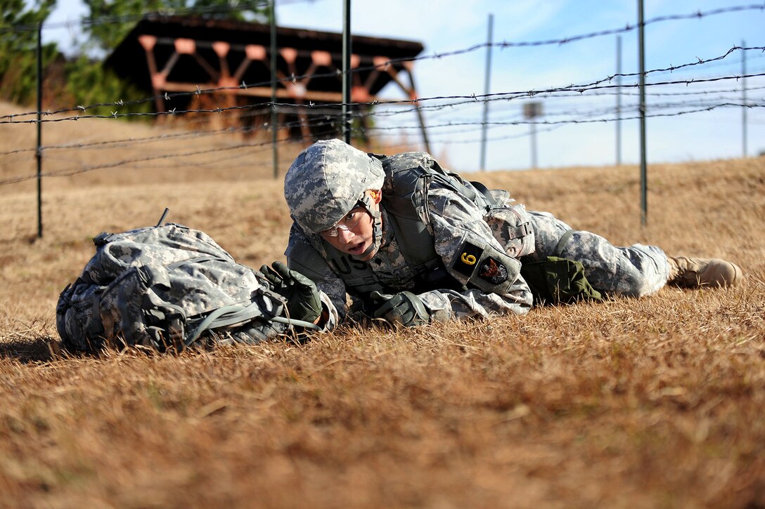 Army Spc. Richard Thomas low crawls under the concertina wire obstacle during the Army’s annual Best Warrior Competition on Fort Lee, Va., Nov. 20, 2013. Thomas, a satellite controller, is assigned to Company B, 53rd Signal Battalion, Fort George Meade, Md.