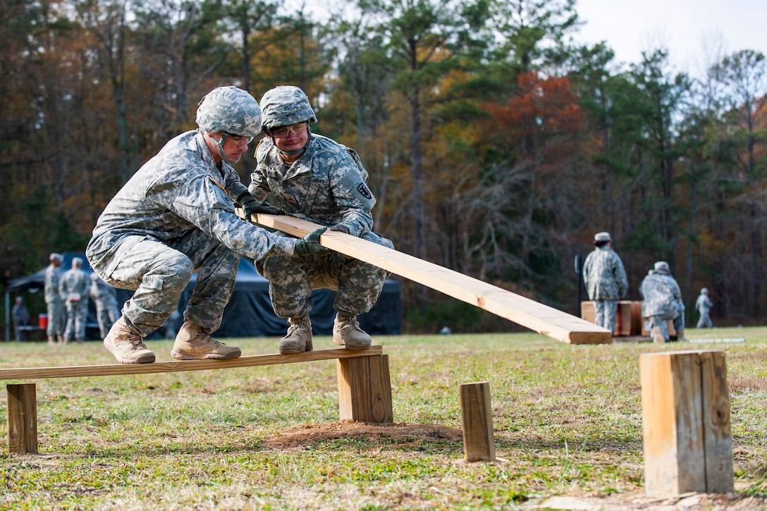 Army Sgt. 1st Class Jason Manella, left, and Pvt. Mercado attempt to extend a plank to overcome an obstacle during the Army’s annual Best Warrior Competition on Fort Lee, Va., Nov. 21, 2013. 