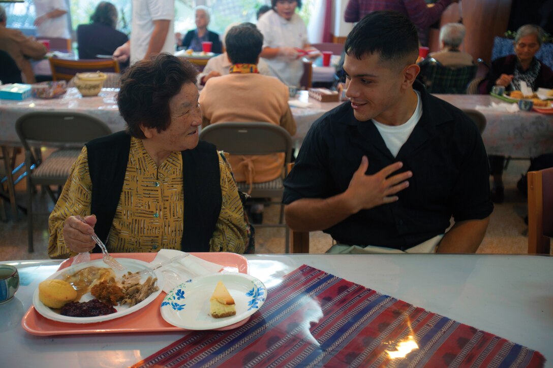 Sae Afuso, left, and 1st Lt. Gregory M. Macias talk to each other during a Thanksgiving-themed meal Nov. 21 at the Hikari Ga Oka nursing home.  Afuso is a resident at the home, and Macias is the officer in charge of the Armory with 7th Communications Battalion, III Marine Expeditionary Force Headquarters Group, III MEF. 