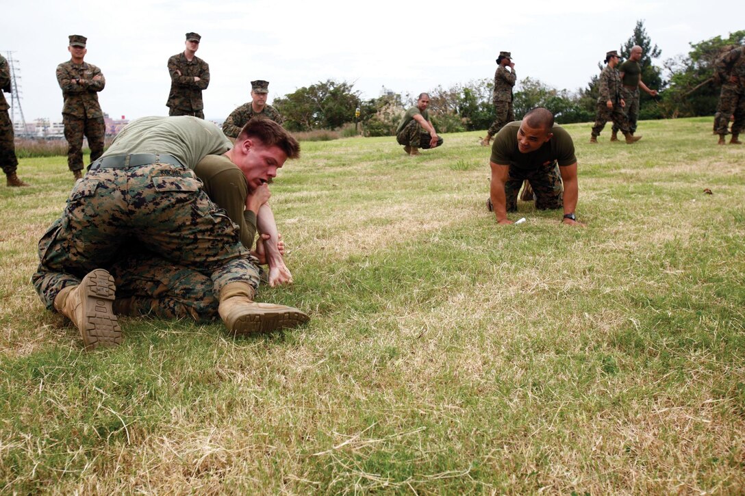 Staff Sgt. Duane C. Pineda, right, assesses a match between Lance Cpl. Brent V. Scheckel and Cpl. Logan B. Kochel during a grappling tournament Nov. 15 at Camp Foster. Pineda is a martial arts instructor with 3rd Medical Battalion, 3rd Marine Logistics Group, III Marine Expeditionary Force. Scheckel is an administrative specialist, and Kochel is a motor vehicle operator. Both are with 3rd Med. Bn.