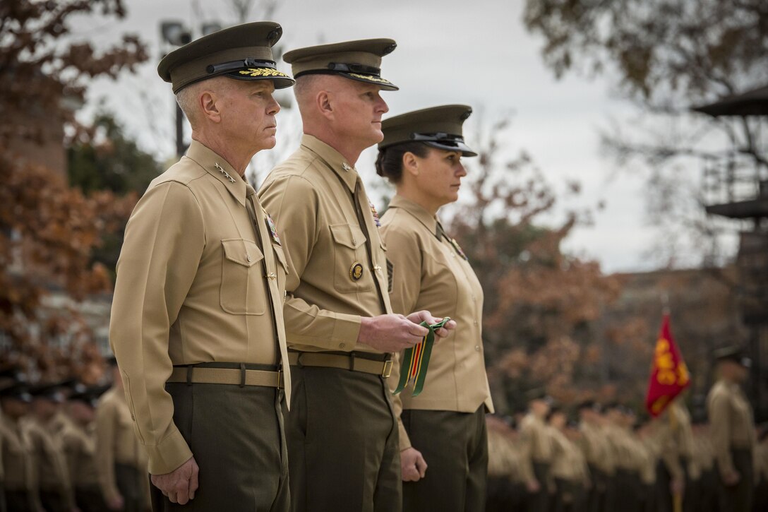 Col. Christian G. Cabaniss, Marine Barracks Washington, D.C. commanding officer, center, holds a Navy Meritorious Unit Commendation streamer flanked by Gen. James F. Amos, commandant of the Marine Corps, left, and Sgt. Maj. Angela M. Maness, the Barracks sergeant major, right,  during an unit award presentation at the Barracks Nov. 22. The Barracks earned the award for its performance while in support of multiple major events around the national capital region. 