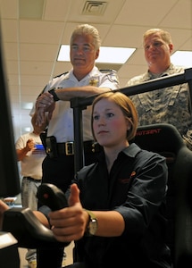 New Orleans resident Jennifer Deblieux, deputy director of STARBASE, demonstrates the flight simulator to Army Maj. Gen. Glenn H. Curtis, adjutant general of the Louisiana National Guard, and St. Bernard Parish Sheriff James Pohlmann following a ribbon cutting ceremony welcoming back the youth-science program STARBASE at Jackson Barracks in New Orleans, Aug. 8, 2012. Introduced in Orleans Parish in 1999, the Louisiana program has since served more than 9,300 students and, as a result of Hurricane Katrina, was relocated to Pineville in Rapides Parish.