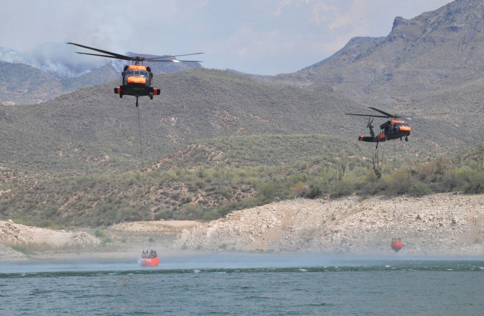 Soldiers from Company A, 2nd Battalion, 285th Aviation Regiment use two UH-60 Black Hawk helicopters to fill Bambi buckets during wildfire suppression efforts in Tonto National Forest, Ariz., Aug. 14, 2012. The aircrews assisted the state and national forestry divisions with battling the Charley Fire near Bartlett Lake and Mistake Peak Fire near Roosevelt Lake throughout the week.