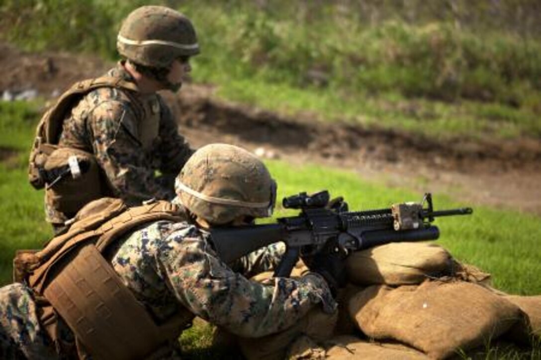 Lance Cpl. Joshua White, a rifleman with 1st Battalion, 3rd Marine Regiment coaches as a personnel safety officer while a Marine shoots an M203 40 mm grenade launcher during new equipment testing for a recently developed sight at Kaneohe Bay range training facility, Nov. 19.
