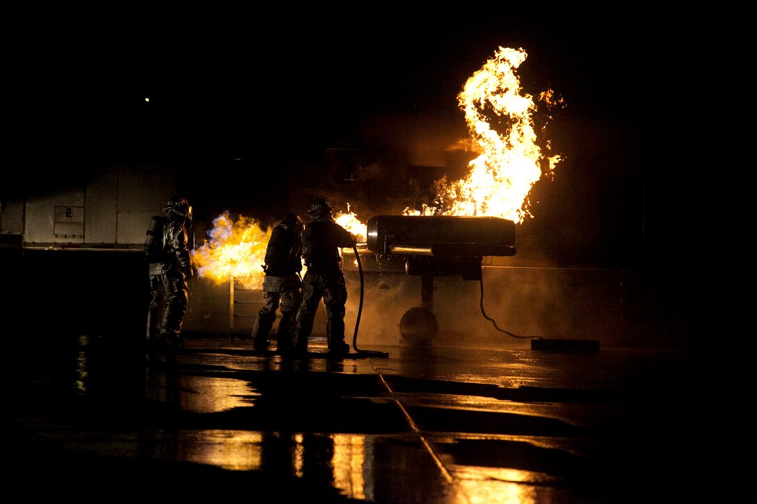 Marines extinguish a fire on a mobile aircraft fire training device Sept. 18 at Marine Corps Air Station Futenma. During the training, a senior ARFF specialist stands near the Marines extinguishing the fire to ensure they practice the proper techniques. The Marines are ARFF specialists with Headquarters and Headquarters Squadron.