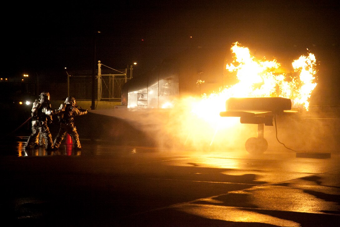 Marines extinguish a fire on a mobile aircraft fire training device Sept. 18 at Marine Corps Air Station Futenma. During the training, a senior ARFF specialist stands near the Marines extinguishing the fire to ensure they practice the proper techniques. The Marines are ARFF specialists with Headquarters and Headquarters Squadron.
