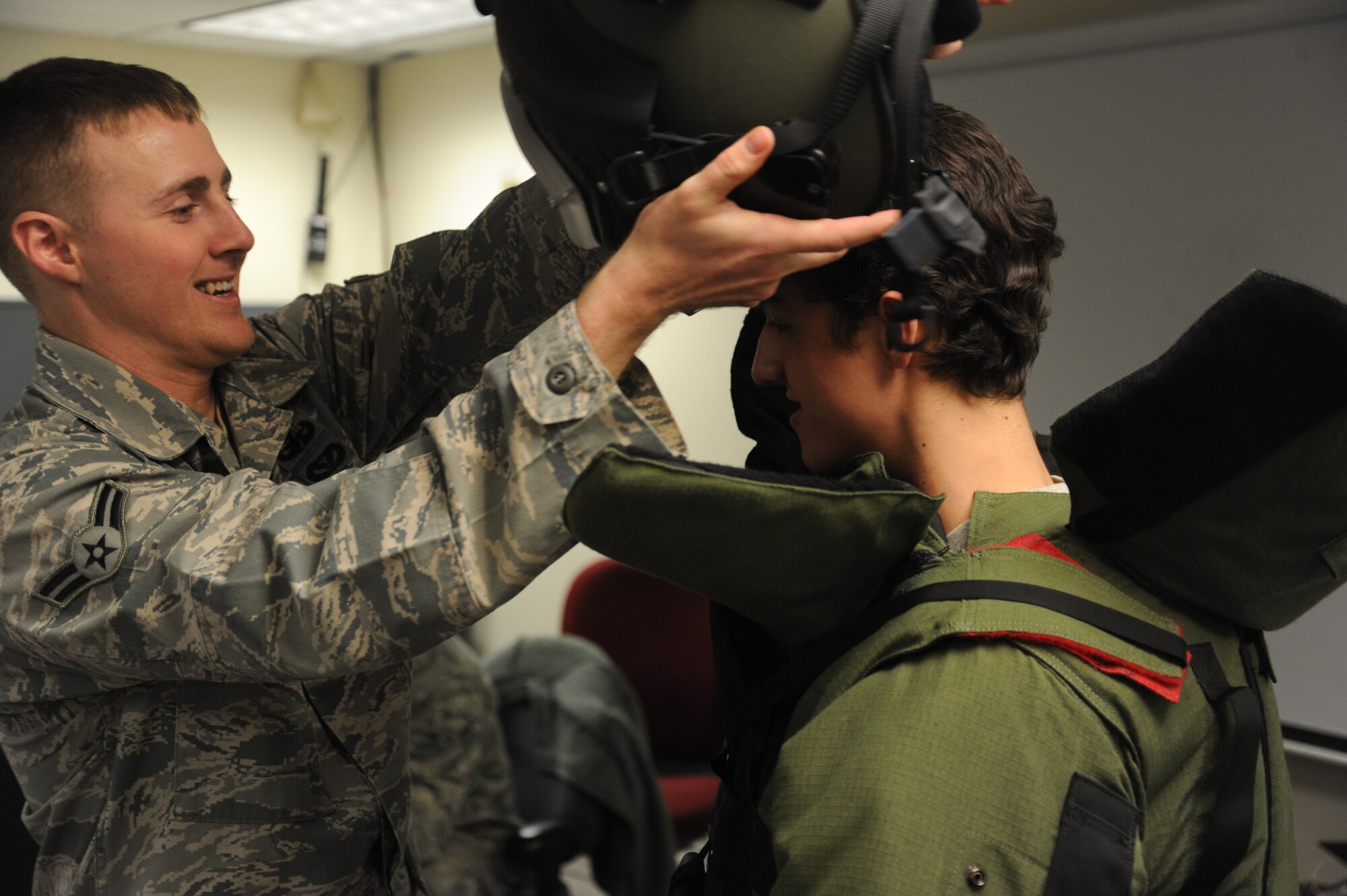 Airman 1st Class Steven Taylor, 92nd Civil Engineer Squadron explosive ordnance disposal technician, helps a West Valley High School student put on an explosive protection suit at Fairchild Air Force Base, Wash., Nov. 22, 2013.  The base tour was conducted to give the students a better understanding of their community.  (U.S. Air Force photo by Airman 1st Class Sam Fogleman/Released)