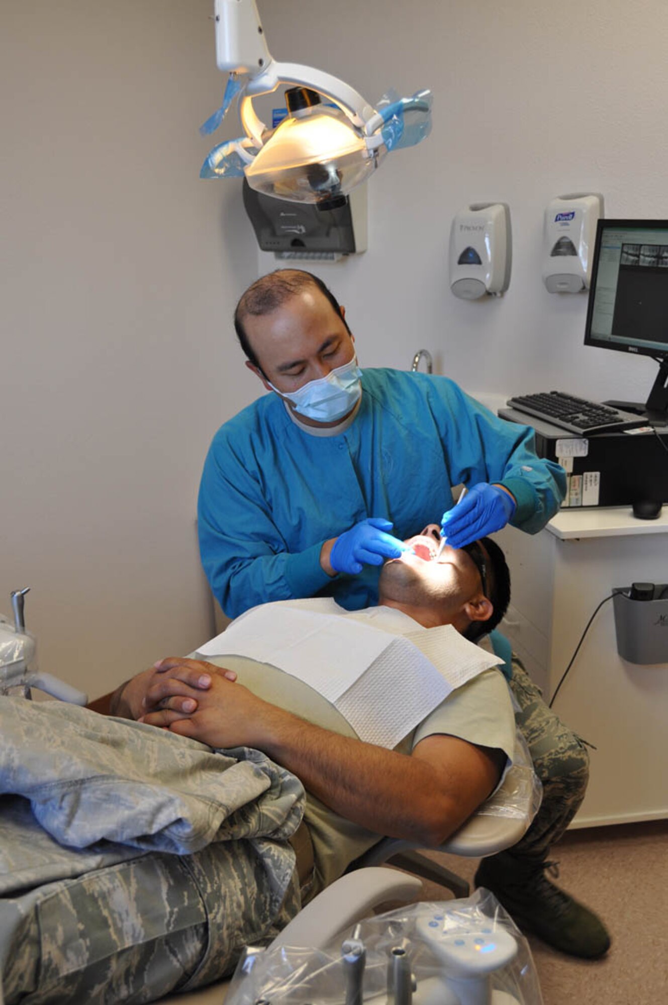 (Left) Maj. John Chan, 926th Aerospace Medicine Squadron dentist, examines a patient at the newly constructed dental clinic Nov. 2. (U.S. Air Force photo/Maj. Jessica Martin)
